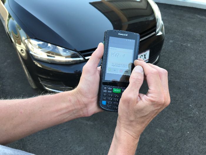 Hand notiert Auto-Kennzeichen auf Handy
