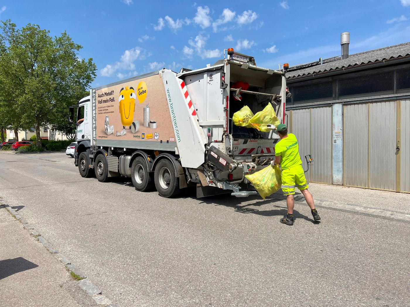 Abfall-LKW mit Mitarbeiter beim Einsammeln der Gelben Scke
