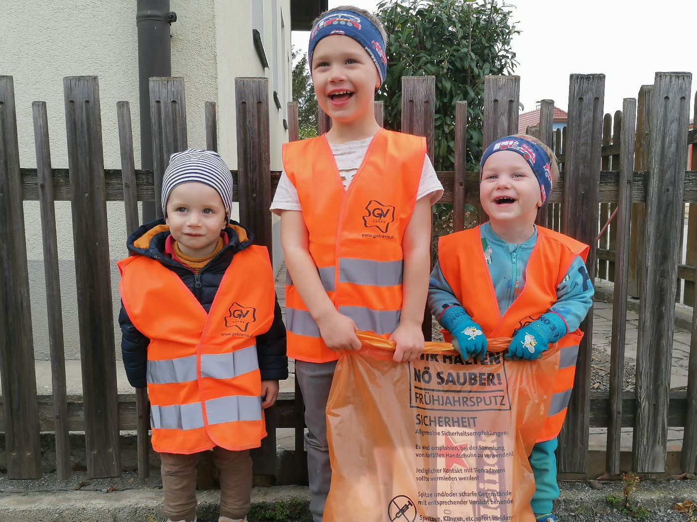 Sebastian, Leon und Jonas in orangen Warnwesten und mit orangem Müllsack